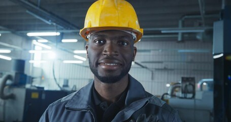 Leinwandbilder - Cinematic Portrait of an African American Man at Work in a Factory. Handsome Black Male Posing for Camera, Looking at Viewer, Smiling. Worker Operating Heavy Duty Machinery, Using Technical Skills