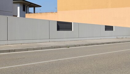 Wall Mural - Long gray concrete fence with black metallic panels. Orange plaster wall on behind, cement sidewalk and city street in front. Background for copy space.