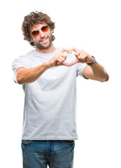 Wall Mural - Handsome hispanic model man wearing sunglasses over isolated background smiling in love showing heart symbol and shape with hands. Romantic concept.