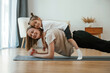 © standret - Lying down on the back of mother. Young woman with little girl are doing yoga at home