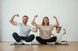 © standret - Showing the biceps, strong. Family of mother, father and daughter are doing yoga at home