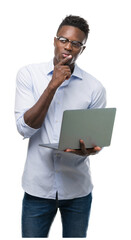 Poster - Young african american businessman using computer laptop serious face thinking about question, very confused idea