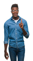 Sticker - Young african american man over isolated background pointing finger up with successful idea. Exited and happy. Number one.