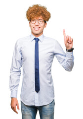 Wall Mural - Young handsome business man with afro wearing glasses showing and pointing up with finger number one while smiling confident and happy.