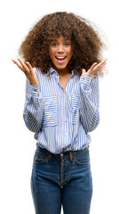 Wall Mural - African american woman wearing a stripes shirt very happy and excited, winner expression celebrating victory screaming with big smile and raised hands