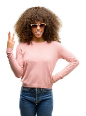 Canvas Print - African american woman wearing pink sunglasses showing and pointing up with fingers number three while smiling confident and happy.