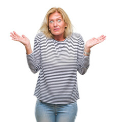 Wall Mural - Middle age blonde woman over isolated background clueless and confused expression with arms and hands raised. Doubt concept.