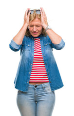 Wall Mural - Middle age blonde woman over isolated background suffering from headache desperate and stressed because pain and migraine. Hands on head.