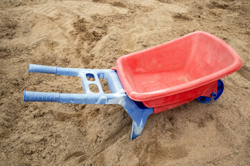 plastic toy wheelbarrow in a sandbox outdoors