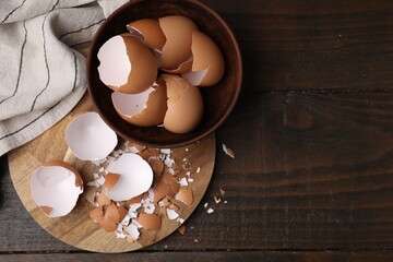 Wall Mural - Pieces of broken eggshells on wooden table, top view. Space for text