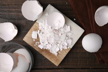 Wall Mural - Pieces of broken eggshells on wooden table, flat lay