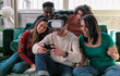 © minoandriani - Trendy people playing with vr glasses on sofa - Virtual reality and wearable tech concept with roommate friends having fun with headset goggles - Generation z digital trends