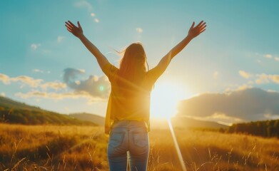 A woman is standing in a field with her arms raised, looking up at the sun. Concept of joy and freedom, as the woman seems to be celebrating the beauty of the moment