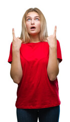 Poster - Young caucasian woman over isolated background amazed and surprised looking up and pointing with fingers and raised arms.