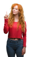 Wall Mural - Young redhead woman surprised with an idea or question pointing finger with happy face, number one