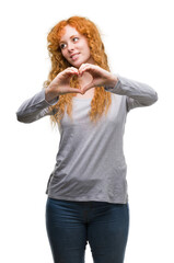 Wall Mural - Young redhead woman smiling in love showing heart symbol and shape with hands. Romantic concept.