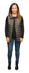 Wall Mural - beautiful middle age woman wearing winter vest relaxed with serious expression on face. simple and n