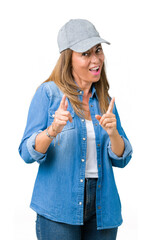 Sticker - Beautiful middle age woman wearing sport cap over isolated background pointing fingers to camera with happy and funny face. Good energy and vibes.