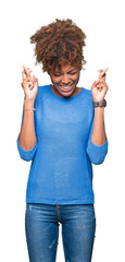 Wall Mural - Beautiful young african american woman over isolated background smiling crossing fingers with hope and eyes closed. Luck and superstitious concept.