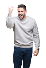 Wall Mural - Young handsome man wearing sweatshirt over isolated background angry and mad raising fist frustrated and furious while shouting with anger. Rage and aggressive concept.