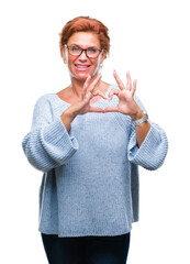 Wall Mural - Atrractive senior caucasian redhead woman wearing glasses over isolated background smiling in love showing heart symbol and shape with hands. Romantic concept.