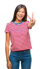 Wall Mural - Young asian woman over isolated background smiling with happy face winking at the camera doing victory sign. Number two.