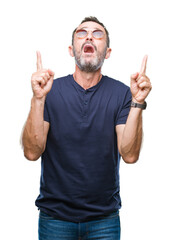 Canvas Print - Middle age hoary senior man wearing sunglasses over isolated background amazed and surprised looking up and pointing with fingers and raised arms.