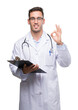 © Krakenimages.com - Handsome young doctor man holding a clipboard doing ok sign with fingers, excellent symbol