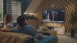 © Framestock - Adult couple talks and watches news broadcast report about US Election Day on the big TV screen sitting on sofa at home. TV display shows playback of breaking news with female Caucasian reporter.