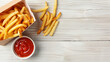 © Silard - Delicious french fries in paper box on white wooden table with copy space for text