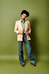 Stylish young African American man in a suit and sunglasses stands confidently in front of a vibrant green wall.