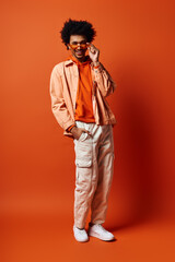 a trendy, emotional young african american man stands confidently against a bright orange background