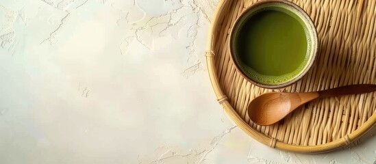 Poster - Top view of a brown Cup filled with Matcha green tea on a bamboo plate with a spoon against a light background with copy space image
