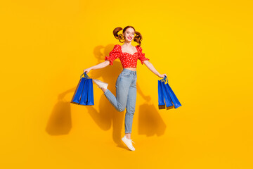 Wall Mural - Full body photo of attractive young woman hold shopping bags jumping dressed stylish red retro clothes isolated on yellow color background