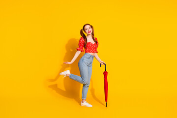 Canvas Print - Full body length photo of young lady in red blouse and jeans holding umbrella rainy weather spring season isolated on yellow color background