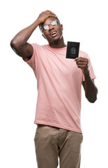 Canvas Print - Young african american man holding canadian passport stressed with hand on head, shocked with shame and surprise face, angry and frustrated. Fear and upset for mistake.