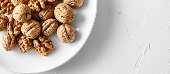 Wall Mural - Top down view of a stack of walnuts on a white plate with a copy space image