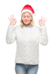 Sticker - Middle age blonde woman wearing christmas hat over isolated background relax and smiling with eyes closed doing meditation gesture with fingers. Yoga concept.