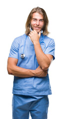 Canvas Print - Young handsome doctor man with long hair over isolated background looking confident at the camera with smile with crossed arms and hand raised on chin. Thinking positive.