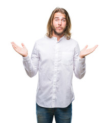 Canvas Print - Young handsome man with long hair over isolated background clueless and confused expression with arms and hands raised. Doubt concept.