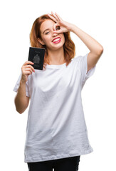 Canvas Print - Young beautiful woman holding passport of canada over isolated background with happy face smiling doing ok sign with hand on eye looking through fingers