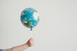 © Aspernaut - Child hand holding planet earth balloon representing climate change awareness and sustainable lifestyle to protect nature