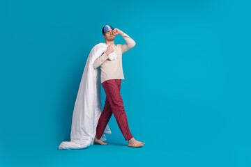 Poster - Full length photo of handsome young guy hold duvet walk rub eye dressed sleepwear sleepover good morning isolated on blue color background