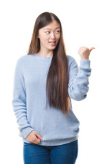 Poster - Young Chinese woman over isolated background smiling with happy face looking and pointing to the side with thumb up.