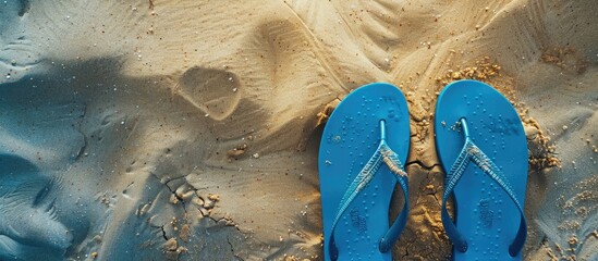 Wall Mural - Overhead view of blue flip flops on a sandy beach with a designated copy space image