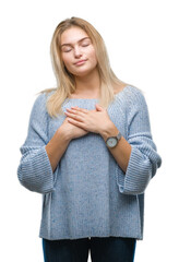 Poster - Young caucasian woman wearing winter sweater over isolated background smiling with hands on chest with closed eyes and grateful gesture on face. Health concept.