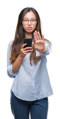 Canvas Print - Young asian woman texting using smartphone over isolated background with open hand doing stop sign with serious and confident expression, defense gesture