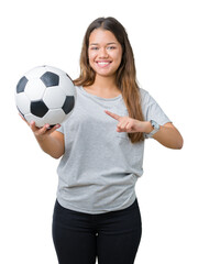 Wall Mural - Young beautiful brunette woman holding soccer football ball over isolated background very happy pointing with hand and finger