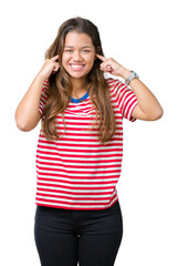 Sticker - Young beautiful brunette woman wearing stripes t-shirt over isolated background covering ears with fingers with annoyed expression for the noise of loud music. Deaf concept.