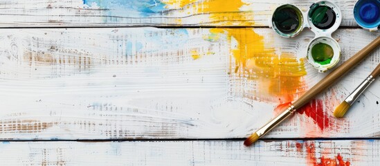 Poster - White wooden table with copy space image adorned with well used watercolor paint and brushes
